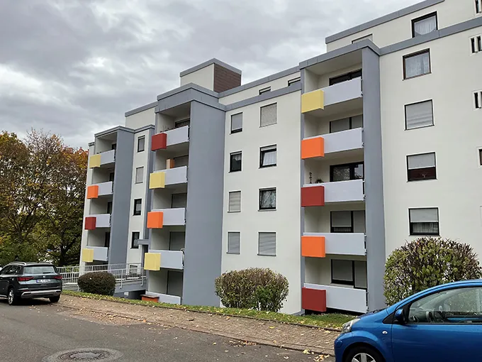 Moderner Wohnblock mit farbiger Balkongestaltung in den Farben Gelb, Orange und Rot. Seitenansicht links