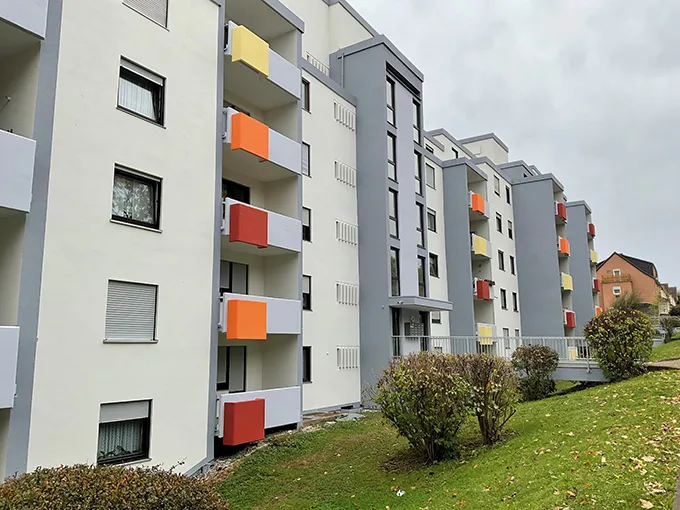 Moderner Wohnblock mit farbiger Balkongestaltung in den Farben Gelb, Orange und Rot. Seitenansicht rechts