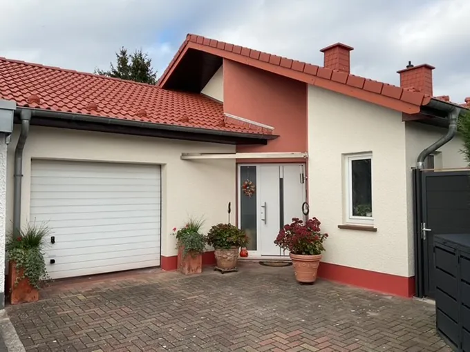 Zweistöckiges Wohnhaus mit rotem Dach und heller, zweifarbiger Fassade, Ansicht Eingangsbereich